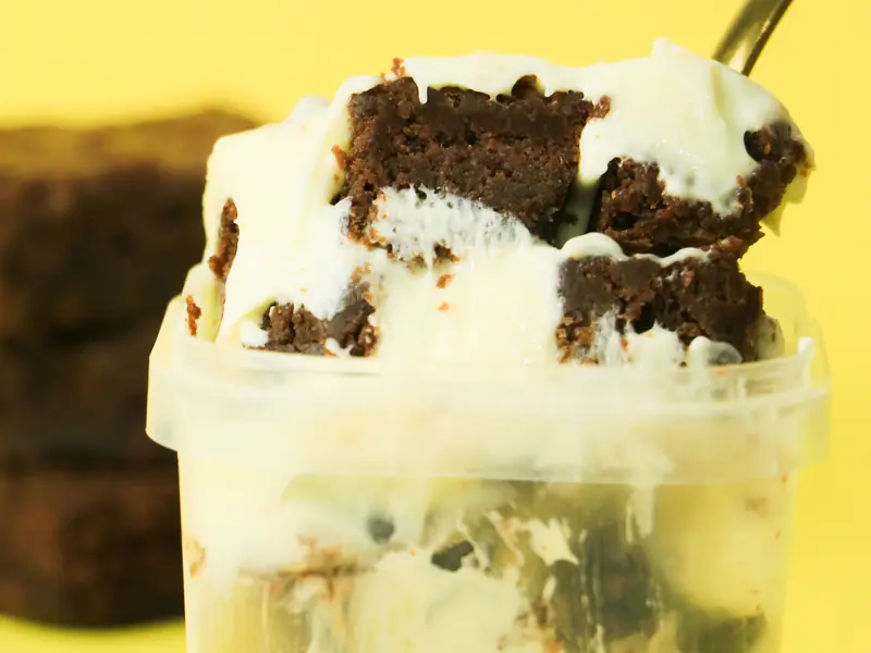 Pote com sobremesa em camadas de creme e pedaços de brownie