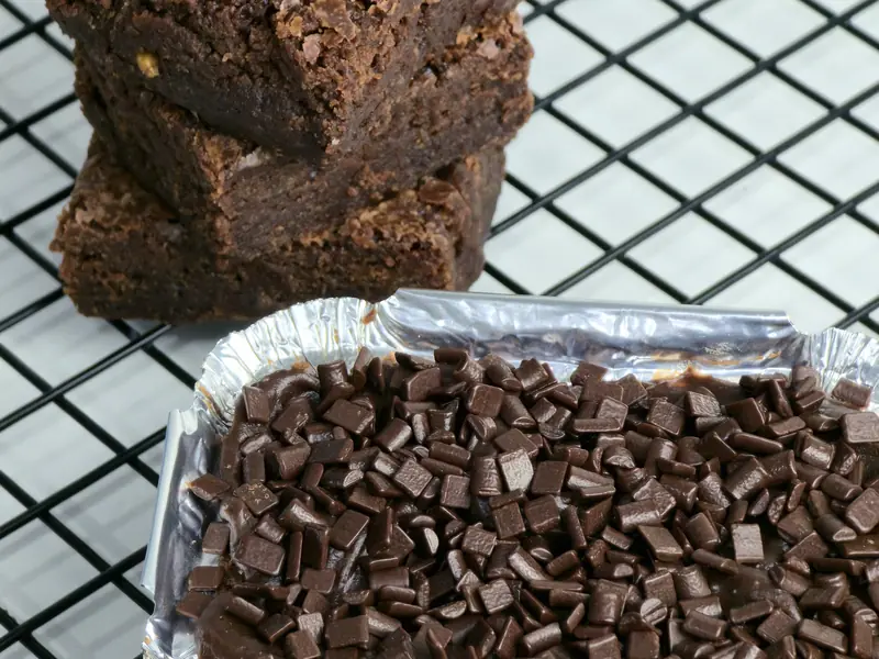 Brownies empilhados sobre grade e uma forma de alumínio cheia de raspas de chocolate